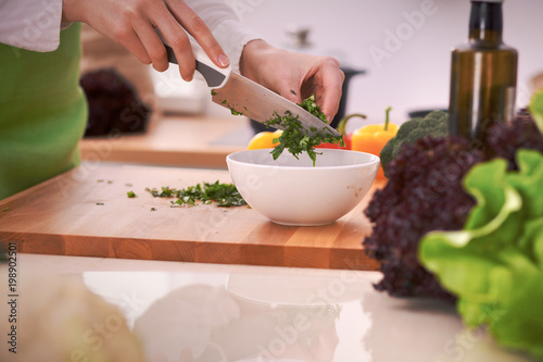 Close Up of human hands cooking vegetable salad in kitchen on the glass table with reflection. Healthy meal, and vegetarian food concept