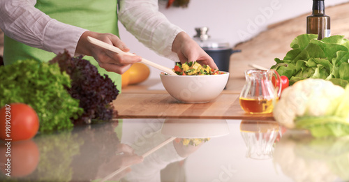 Close Up of human hands cooking vegetable salad in kitchen on the glass table with reflection. Healthy meal, and vegetarian food concept