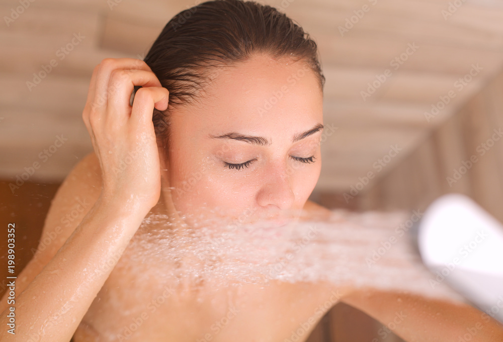 Naklejka premium Young beautyful woman under shower in bathroom.
