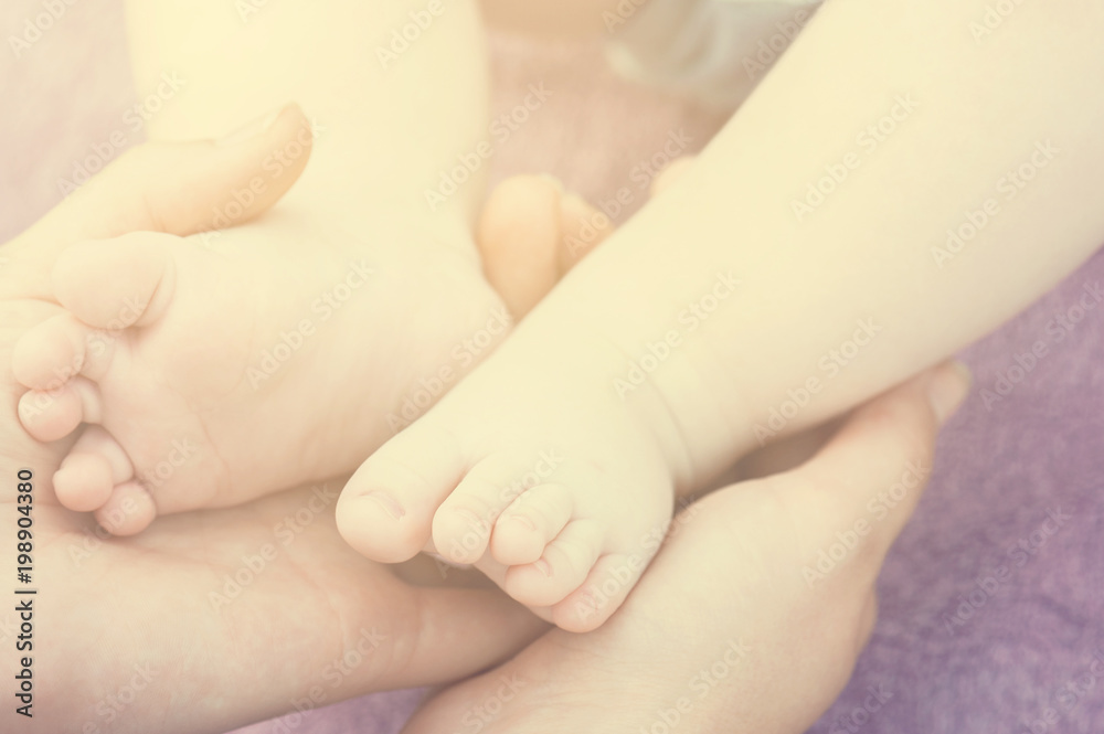 Baby feet in mother hands. Tiny newborn baby feet, concept of happy family. Fake color tone of photo.. Baby feet in mother hands. Tiny newborn baby feet, concept of happy family. Fake color tone of photo..