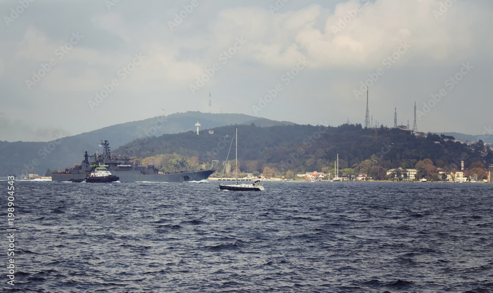 Motorboat and war ship cross Bosphorus strait in Tarabya area of Istanbul.