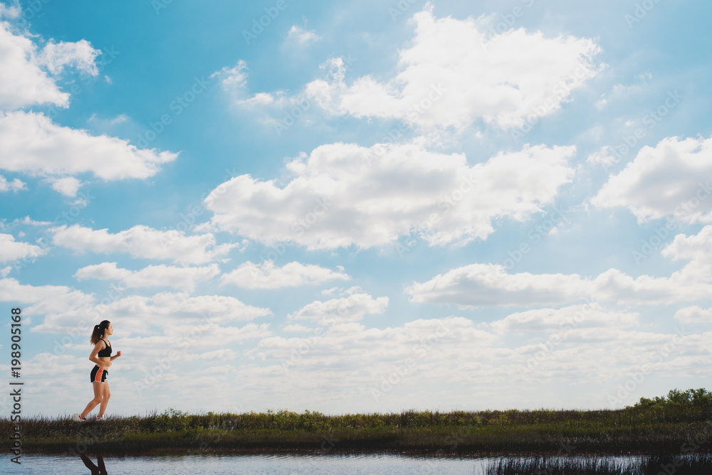 Obraz premium Running girl on a green field and bright sky