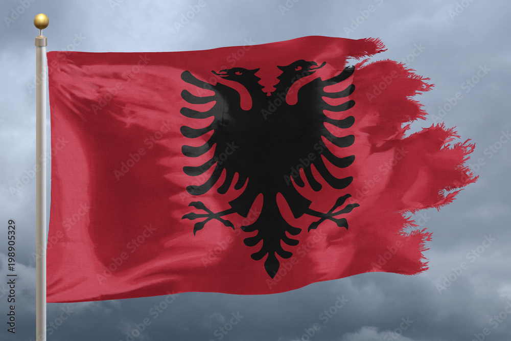 Albania flag with torn edges in front of a stormy sky Albania flag with torn edges in front of a stormy sky