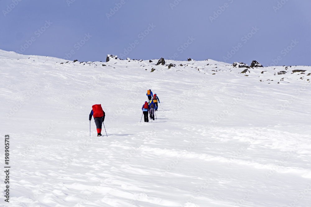 group of hikers on snow-covered mountain slope under a bright blue sky