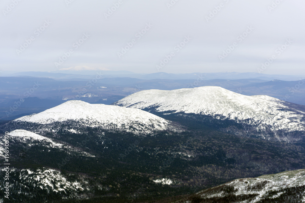 treeless mountain peaks of the Northern Urals, surrounded by taiga in winter from a bird's eye view