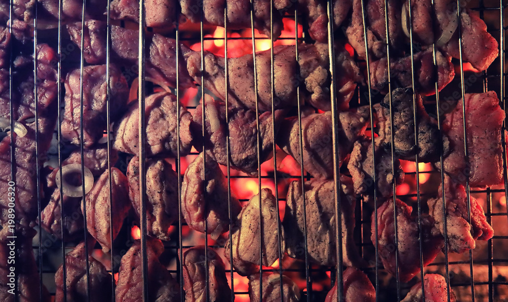 Slices of chopped meat in a grate for cooking barbecue on charco
