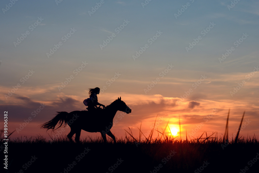 Romantic equine and girls silhouette on horse hiking with red rising sun on horizon. Galloping horse with female rider on beautiful colorful sunset background. 