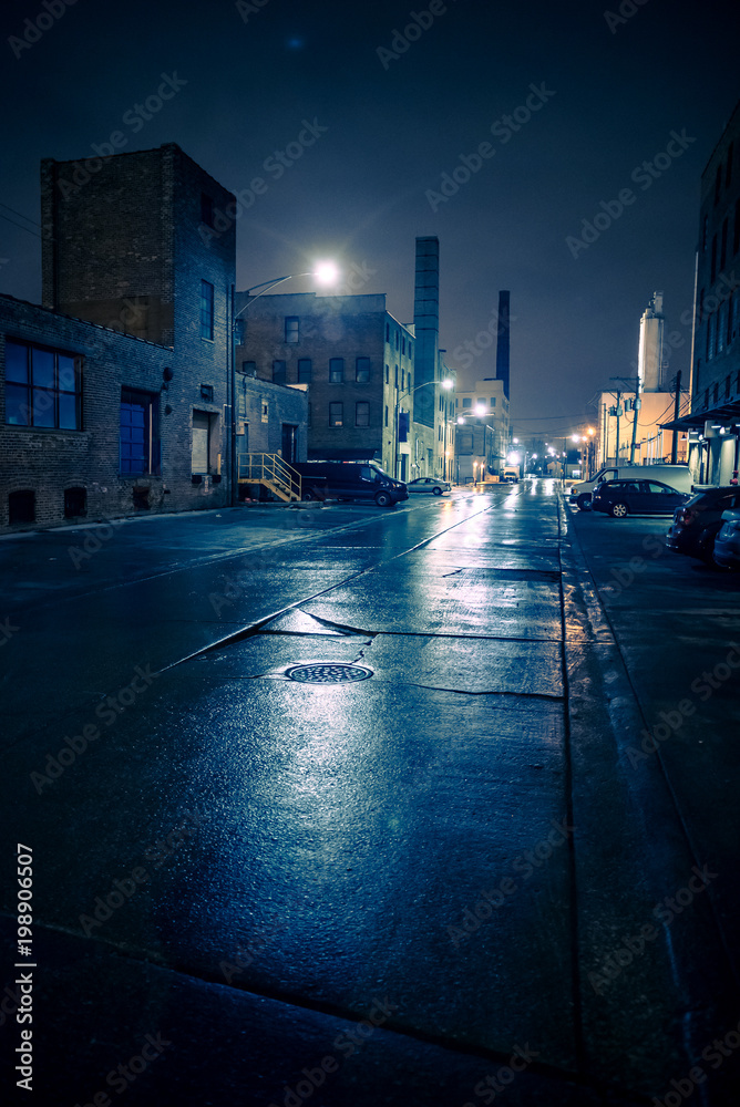 Obraz premium Foggy industrial urban street city night scenery in Chicago with vintage warehouses, factories and smokestacks after a rain.