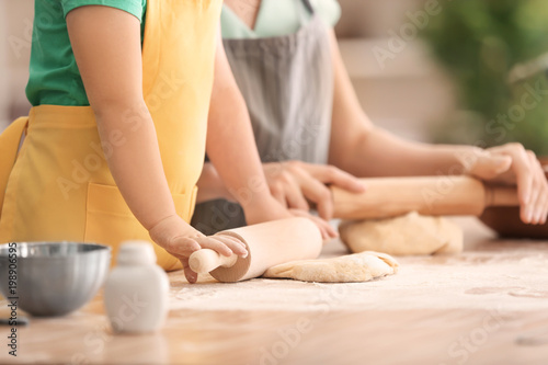 Mother and daughter with dough at table in kitchen