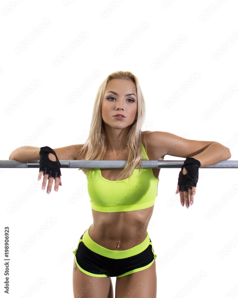 A sportive beautiful girl is standing leaning on sports equipment in the gym. Weight loss. Sexual posture. Sports nutrition. Brilliant skin. Isolate. Free space. The concept A sportive beautiful girl is standing leaning on sports equipment in the gym. Weight loss. Sexual posture. Sports nutrition. Brilliant skin. Isolate. Free space. The concept