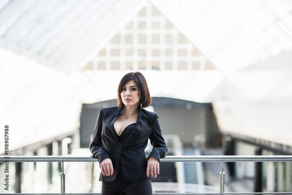 A portrait of a young business woman on handsrail in an office hall