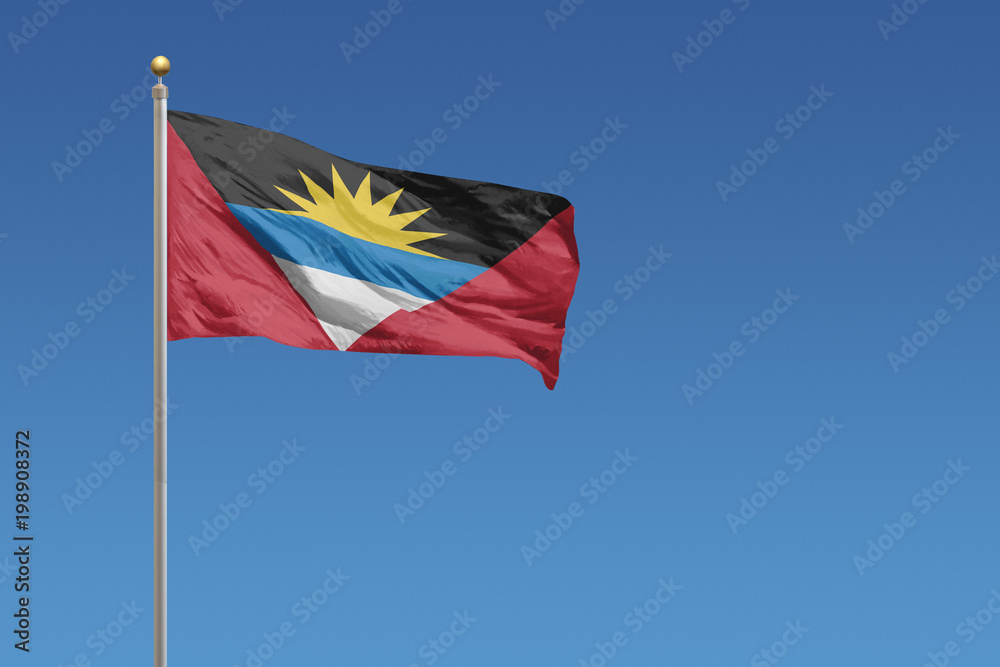 Naklejka premium Antigua and Barbuda flag on a clear blue sky day