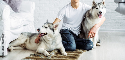 boy is hugging husky dog in shirt and jeans in the room