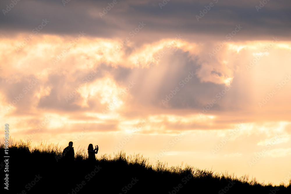 Silhouette scene of a couple enjoy with their drone at sunset on the top of Mt. Eden, Auckland, New Zealand. Silhouette scene of a couple enjoy with their drone at sunset on the top of Mt. Eden, Auckland, New Zealand.