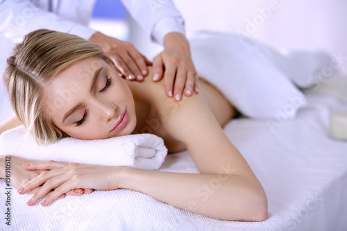 Young woman lying on a massage table,relaxing with eyes closed. Woman. Spa salon