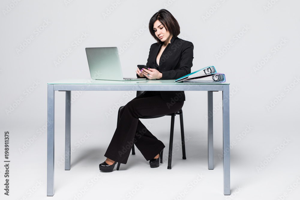 Full length portrait of a happy young woman working with computer in call center typing on phone over white background