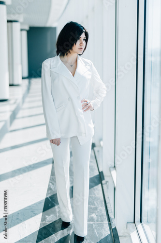 Full length portrait of serious young business woman professional standing in office photo