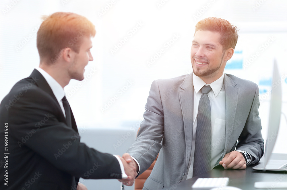 handshake of business partners sitting at a Desk. handshake of business partners sitting at a Desk.