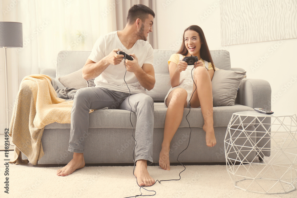 Happy Couple Sitting On The Sofa Playing Video Games Using