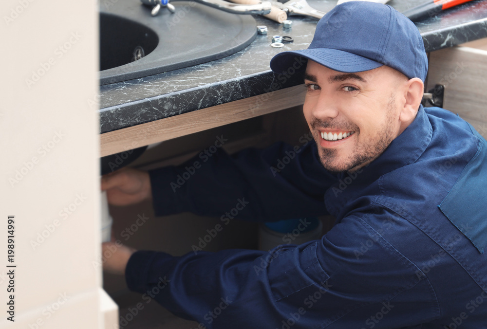 Professional male plumber replacing sink trap indoors Professional male plumber replacing sink trap indoors