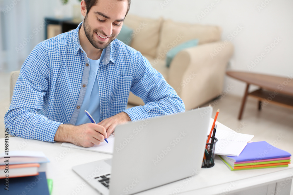 Student with laptop studying at table indoors Student with laptop studying at table indoors
