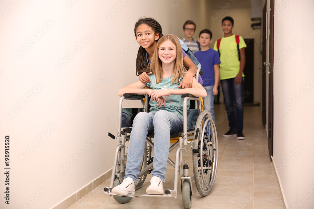 Classmate helping girl in wheelchair at school corridor Classmate helping girl in wheelchair at school corridor