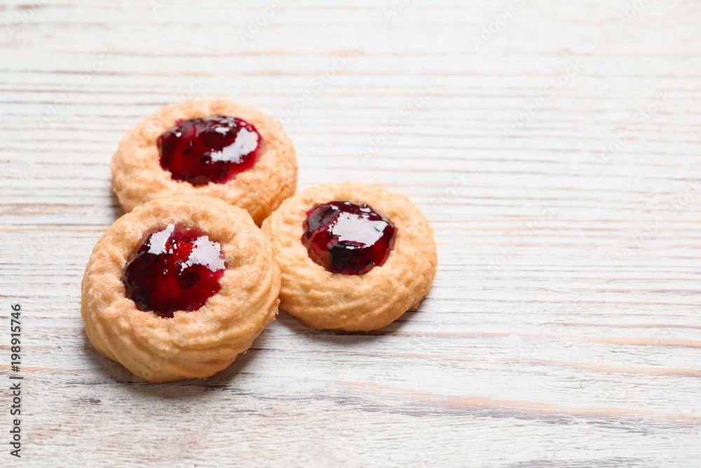 Tasty cookies with jam on wooden background