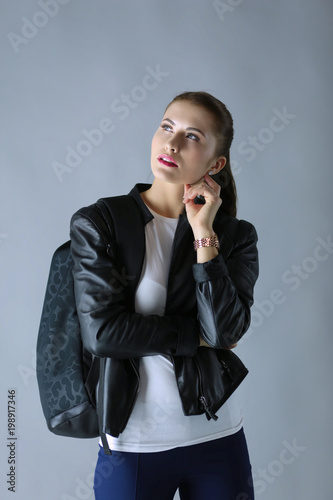 portrait of beautiful young brunette woman in stylish black jacket on gray. photo