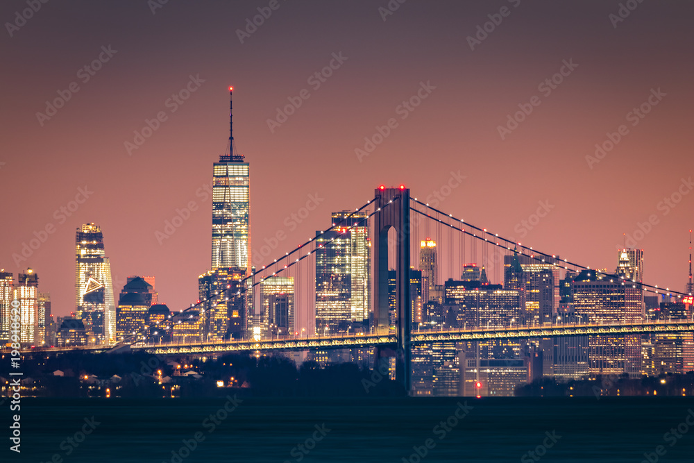 Manhattan skyline at dawn rises behind Verazzano Bridge