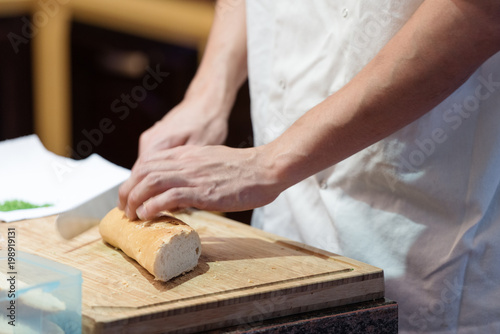 Cutting bread by knife in the kitchen