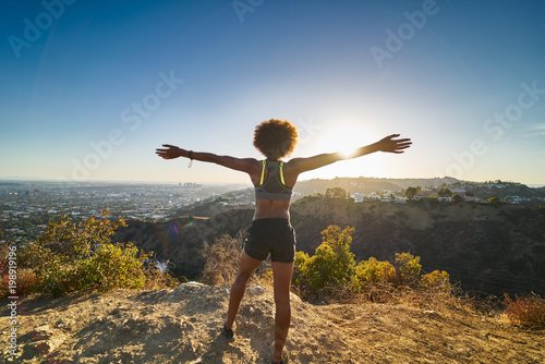 athletic african american woman celebrating reaching top of runyon canyon with arms open