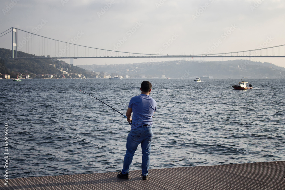 Fisherman by Bosphorus in Istanbul. FSM bridge is in the background.