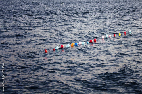 Balloons are lined up on water.