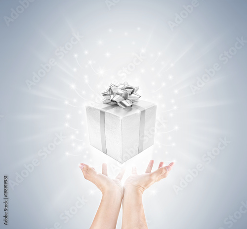 Fototapeta Naklejka Na Ścianę i Meble -  hand with silver gift box and magic twinkles