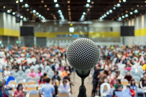 Microphone over the Abstract blurred photo of conference hall or seminar room in Exhibition Center background with Speakers on the stage and attendee background, Business meeting and education concept