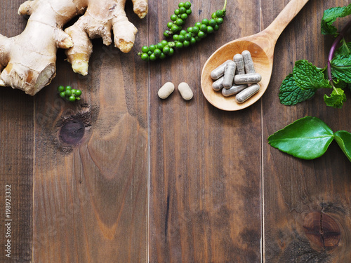 herbal pills in wooden spoon and herbs photo