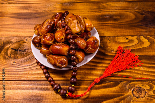 Date fruits and rosary on wooden table