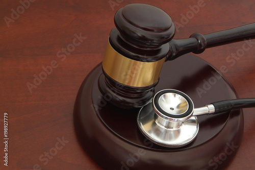 Wooden gavel and stethoscope on wooden background with copyspace