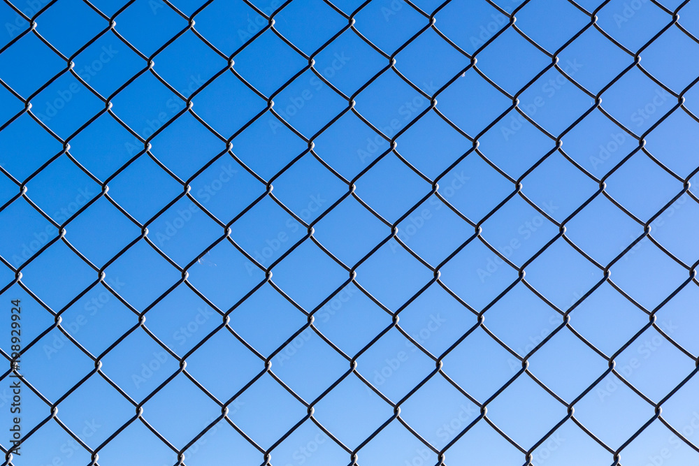 Close up of chain wire fence against blue sky Close up of chain wire fence against blue sky