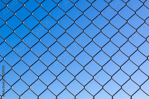 Close up of chain wire fence against blue sky