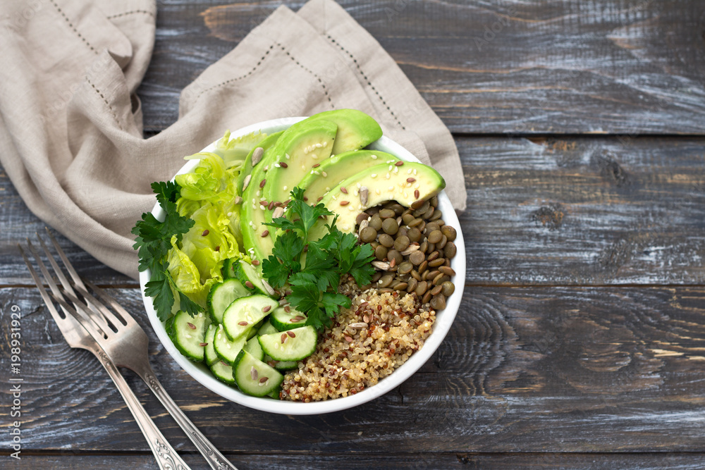 Green Buddha Bowl with lentils, quinoa, avocado, cucumber, fresh lettuce, herbs and seeds. Delicious healthy balanced eating. On a wooden background, top view, free space Green Buddha Bowl with lentils, quinoa, avocado, cucumber, fresh lettuce, herbs and seeds. Delicious healthy balanced eating. On a wooden background, top view, free space