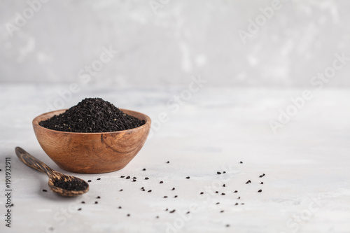 Nigella sativa or Black cumin in wooden bowl on white background, copy space