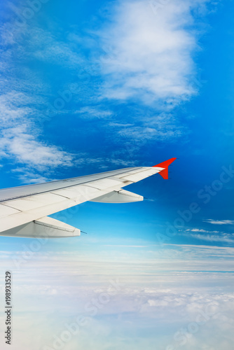 Wing of airplane flying above the clouds in the sky