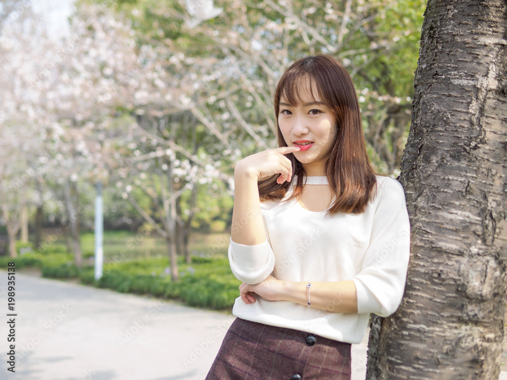 Outdoor portrait of beautiful young Chinese girl smiling among blossom cherry tree brunch in spring garden, beauty, summer, emotion, expression and people concept. Outdoor portrait of beautiful young Chinese girl smiling among blossom cherry tree brunch in spring garden, beauty, summer, emotion, expression and people concept.