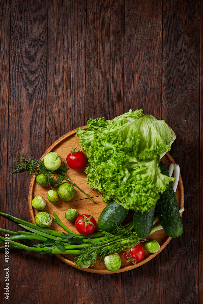 Vegetarian still life of fresh vegetables on wooden plate over rustic background, close-up, flat lay. Vegetarian still life of fresh vegetables on wooden plate over rustic background, close-up, flat lay.