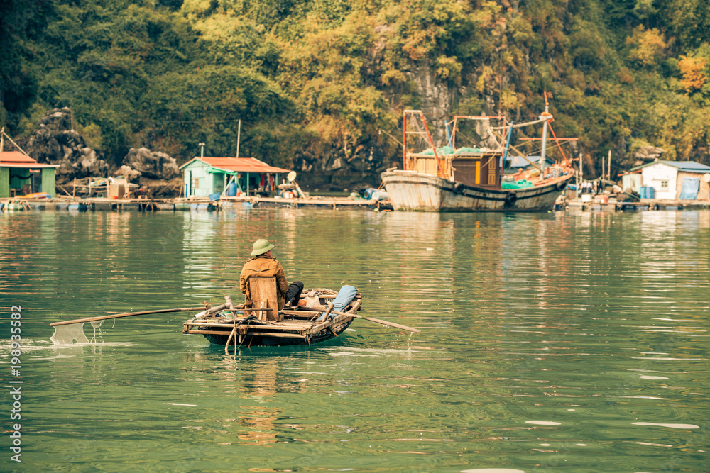 a fisherman rows with his feet in Ha Long Bay Vietnam