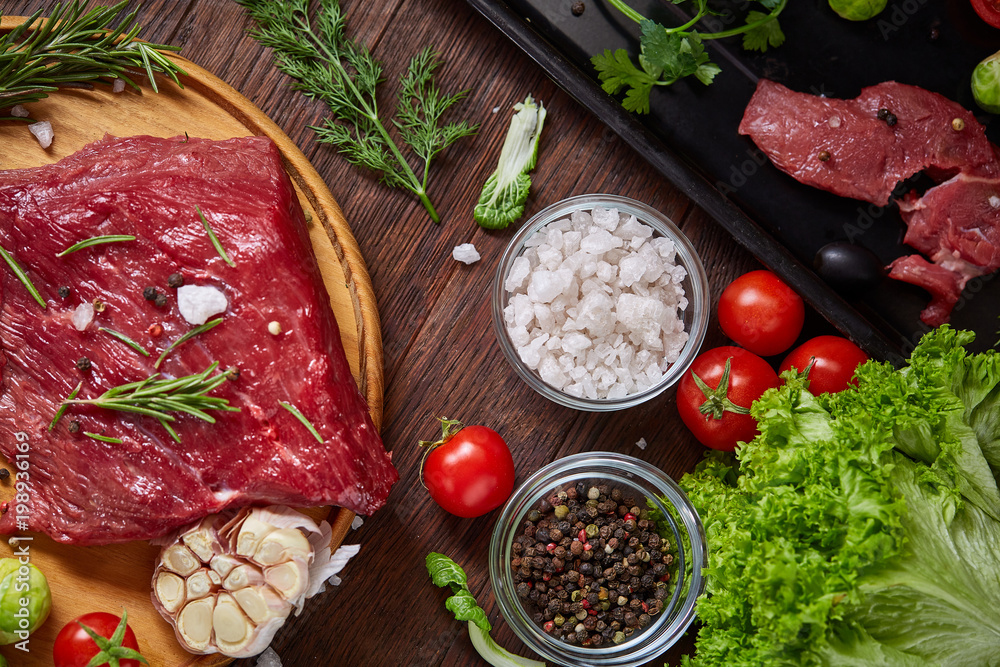 Fototapeta Still life of raw beef meat with vegetables on wooden plate over vintage background, top view, selective focus