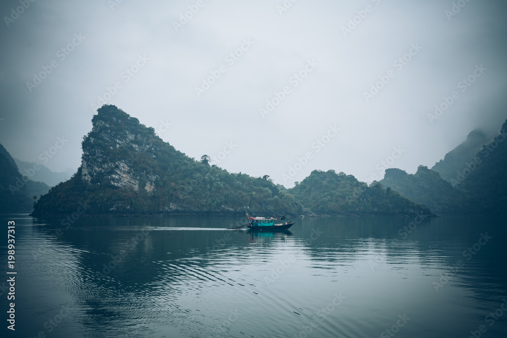 a fisherman in his boat in Ha Long Bay Vietnam