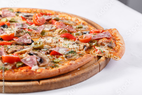 Italian kitchen and cooking concept. Hot tasty sliced with ham, sausage, jalapenos, mushrooms, tomato. Eat delivery concept.