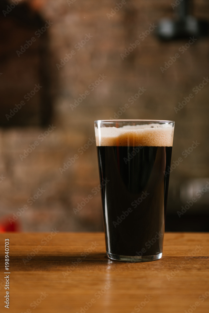close-up view of glass with delicious dark beer on table in pub